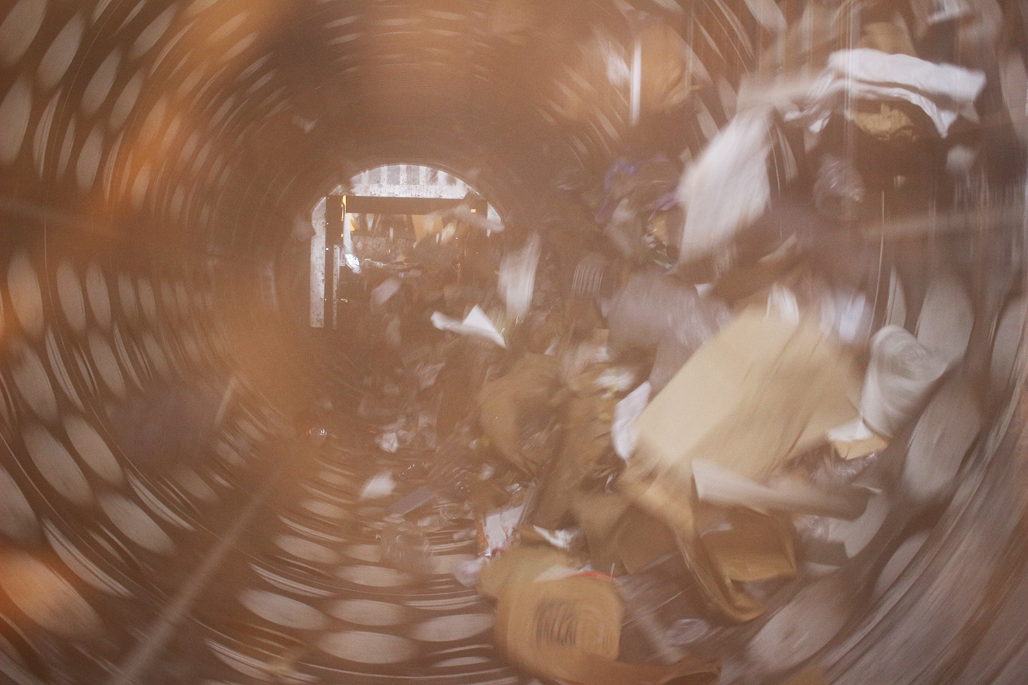 Une fois le contenu déversé dans les locaux de l’usine, les déchets de la poubelle jaune sont acheminés via la trémie d’alimentation qui pousse les déchets jusqu’au trommel. Cette machine permet un tri mécanique des déchets par taille et de récupérer les « matières fines », y compris en acier et en aluminium © Globe Reporters