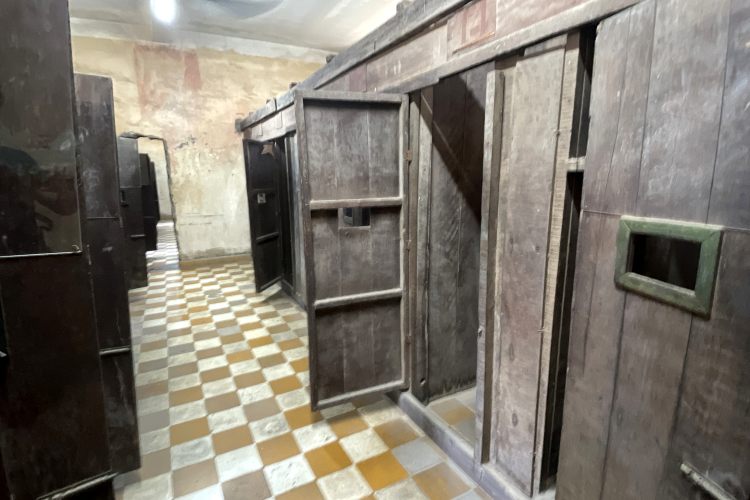 Cellules individuelles en bois construites à l’intérieur des anciennes salles de classe de la prison de Tuol Sleng (S21) © Globe Reporters